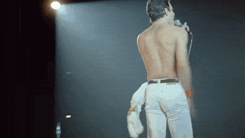 a shirtless man is singing into a microphone on stage