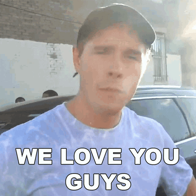 a man wearing a tie dye shirt and a baseball cap says we love you guys
