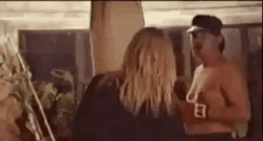 a man and a woman are standing next to each other in a room with a surfboard in the background .