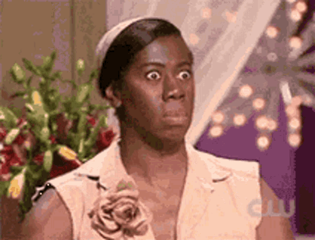 a woman with a flower in her hair is making a funny face in front of flowers .