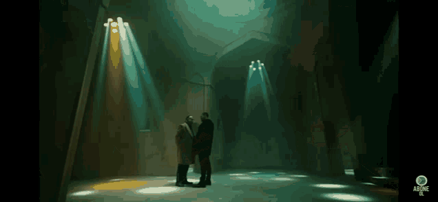 two men are standing in a dark room with lots of lights shining on them .