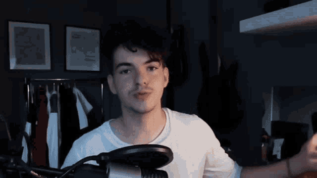 a young man is talking into a microphone in a dark room