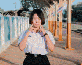 a girl in a white shirt and black skirt stands in front of a row of poles