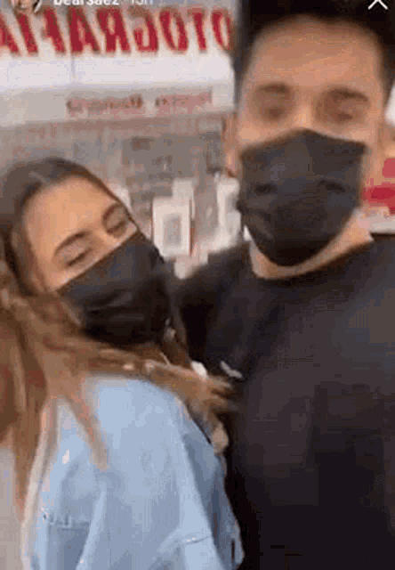 a man and a woman wearing face masks are standing next to each other in front of a store .