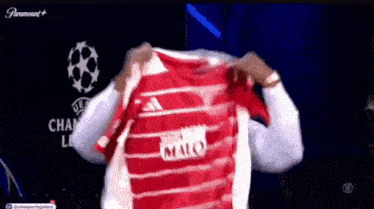 a man is holding up a red shirt that says marco