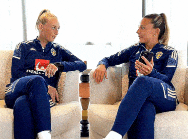 two women sitting on a couch with one wearing a shirt that says svensk