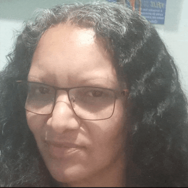 a woman wearing glasses looks at the camera in front of a sign that says ' sleek ' on it