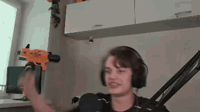 a young man wearing headphones is holding a water gun in his hand .