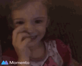 a little girl is giving the middle finger and the word momento is on the bottom right