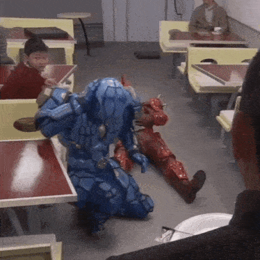 a man in a robot costume is kneeling down in a diner