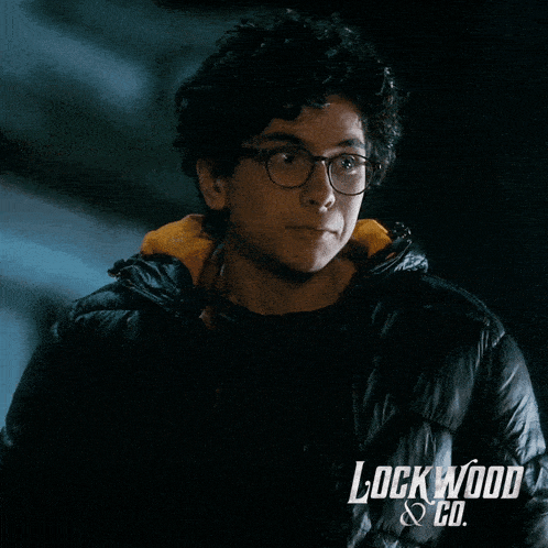 a man wearing glasses and a black jacket with lockwood & co. written on the bottom