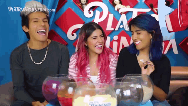 a group of people are laughing in front of a sign that says " platica polinesia.com "