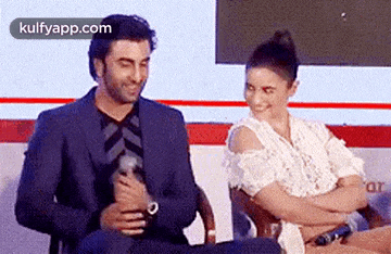 a man and a woman are sitting next to each other and smiling .