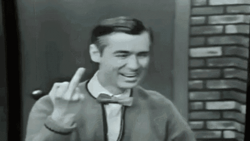 a man wearing a bow tie and a sweater is giving the middle finger