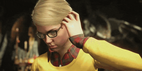 a woman wearing glasses and a yellow shirt holds her hair