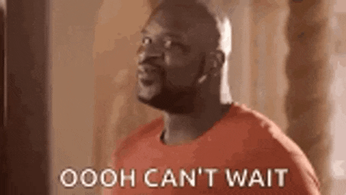 a bald man in a red shirt is standing in front of a wall and says `` ooh can 't wait '' .