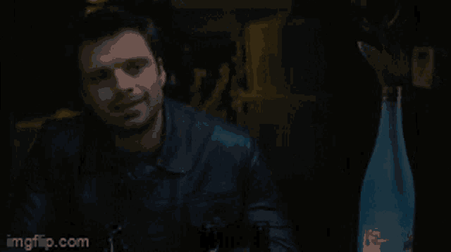 a man in a leather jacket is smiling in a dark room with imgflip.com in the corner