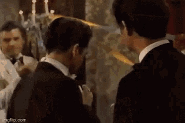 two men in suits are standing next to each other in a room and talking .