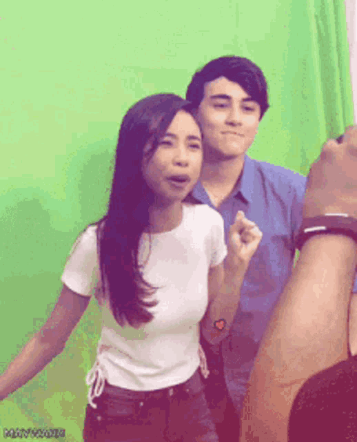 a man and a woman standing in front of a green screen