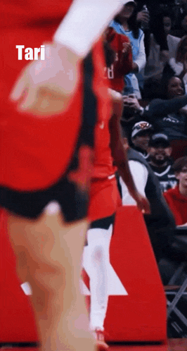 a basketball player is standing in front of a crowd and the word tari is on the bottom right