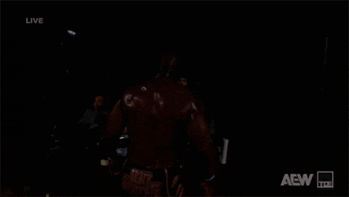 a man is standing in the dark with aew written on the bottom