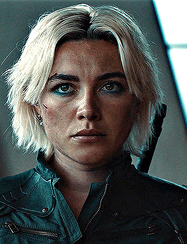 a close up of a woman 's face with blonde hair and a black jacket .