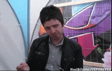 a man in a black jacket is standing in front of a graffiti wall and eating something .