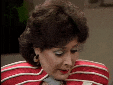 a woman wearing a red and white striped jacket and earrings is looking down .