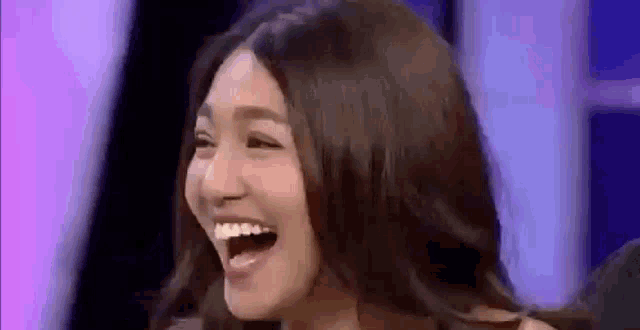 a woman is laughing with her mouth open .