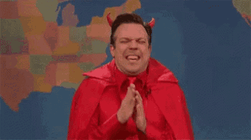 a man in a red devil costume is praying with his hands folded .