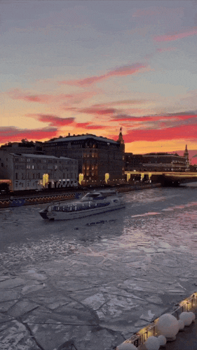 a boat floating on a frozen river with a sunset in the background