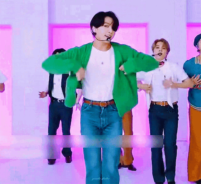 a man in a green cardigan is dancing in front of a group of people