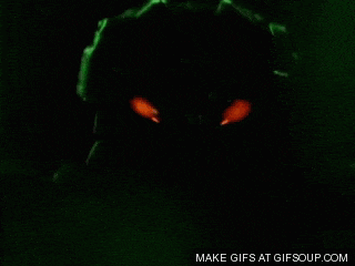 a person is standing in a dark room with a green light coming out of their eyes .