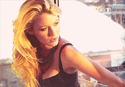 a woman with long blonde hair is wearing a black tank top