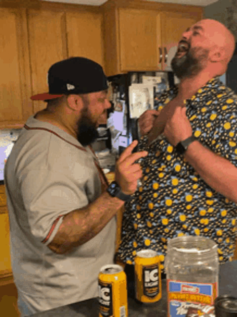 two men are standing in a kitchen with a can of ic energy drink on the counter