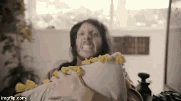 a man with a beard is laying on a bed holding a pillow with yellow tassels
