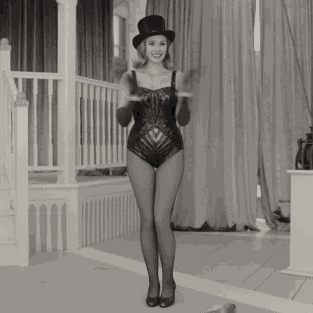 a black and white photo of a woman wearing a top hat and tights