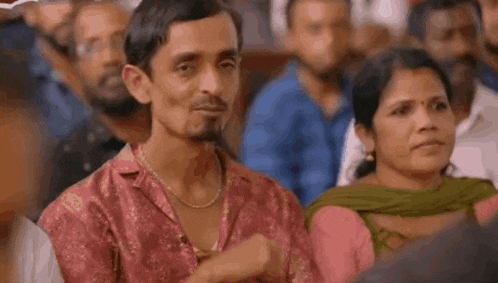 a man and a woman are sitting in a crowd of people . the man is smiling and the woman is crying .