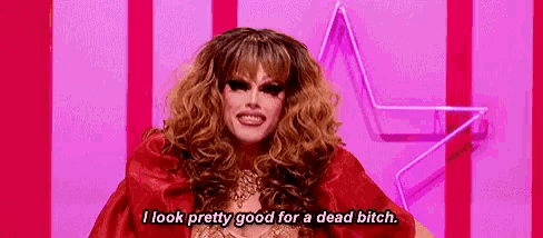 a drag queen is standing in front of a pink star and says `` i look pretty good for a dead bitch '' .