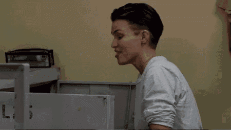 a woman in a white shirt is sitting in front of a locker in a room .