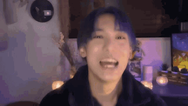 a young man with blue hair is making a funny face while sitting in front of a television .