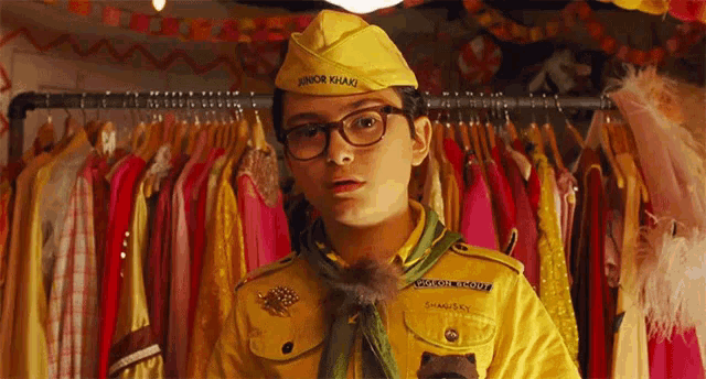 a boy scout in a yellow uniform with junior guard written on his hat