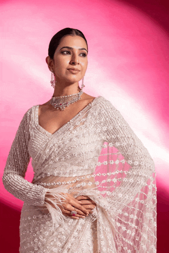 a woman is wearing a white saree and a pearl necklace