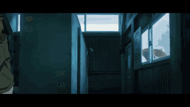 a woman stands in a dark hallway looking out a window with a sticker on the wall that says ' a '