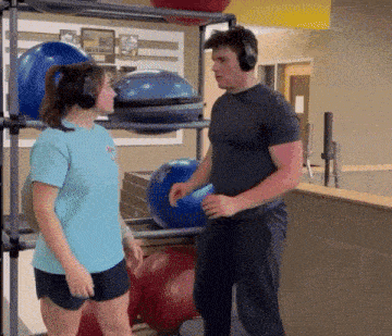 a man and a woman wearing headphones are standing in a gym