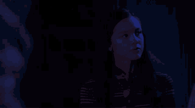 a blurry picture of a man standing in the dark with a blue light behind him .