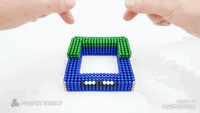 a person is playing with a blue and green magnet world game