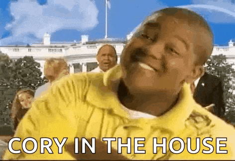 a man in a yellow shirt is standing in front of a white house and smiling .