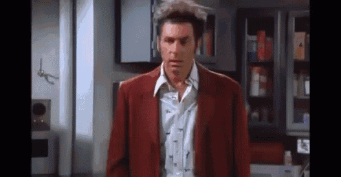 a man in a red jacket and white shirt is standing in a room .