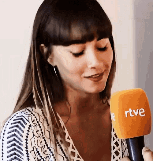 a woman is holding an orange microphone that says rtve on it